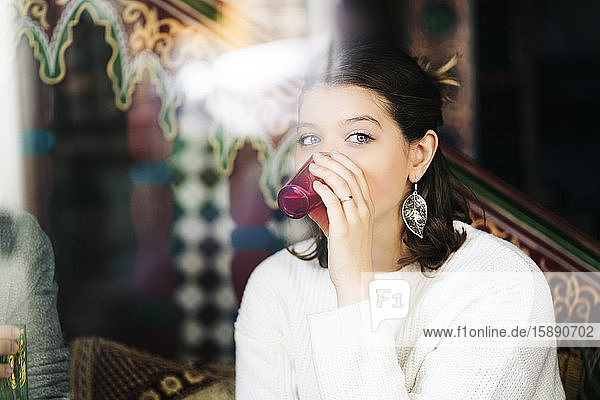 Porträt einer jungen Frau  die in einem Teegeschäft Tee trinkt