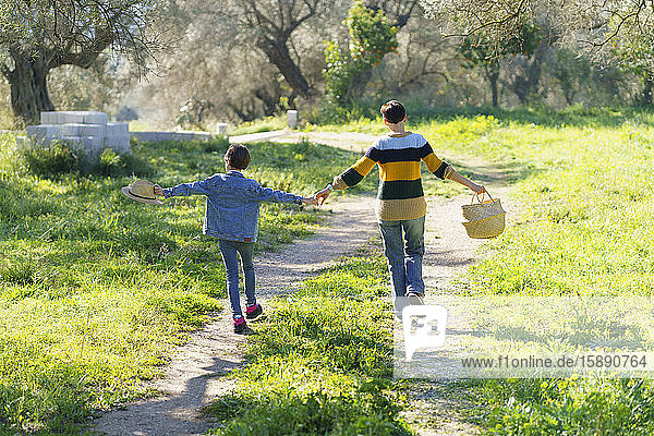 Mother and daughter walking hand in hand on a rural path