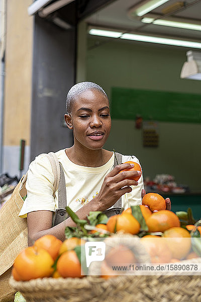 Frau kauft Mandarinen in einer Markthalle