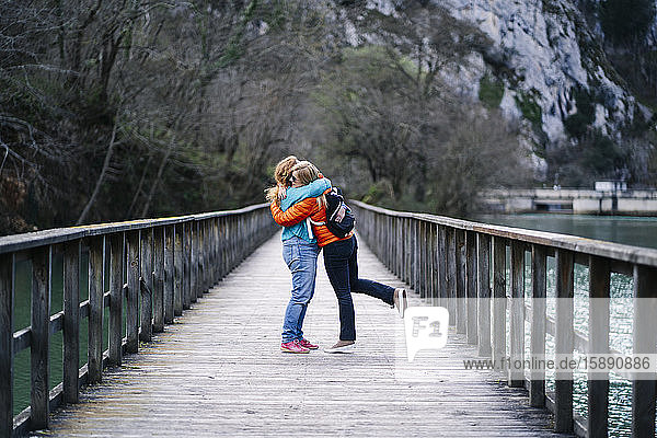 Zwei glückliche Frauen stehen auf der Strandpromenade und umarmen sich  Valdemurio-Stausee  Asturien  Spanien