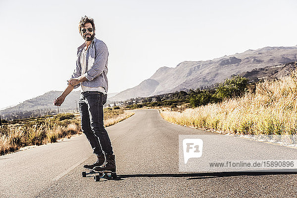 Mann fährt Skateboard auf der Landstraße