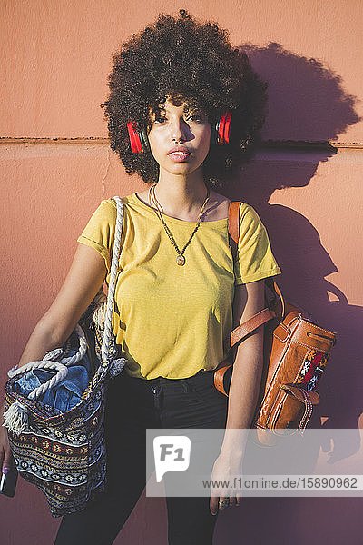 Porträt einer jungen Frau mit Afrofrisur  die mit Kopfhörern Musik hört