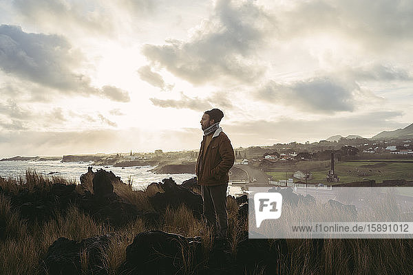 Mann steht in wilder Landschaft an der Küste  Insel Sao Miguel  Azoren  Portugal