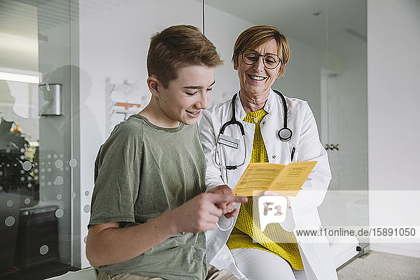 Doctor explaining vaccination to teenage boy in medical practice