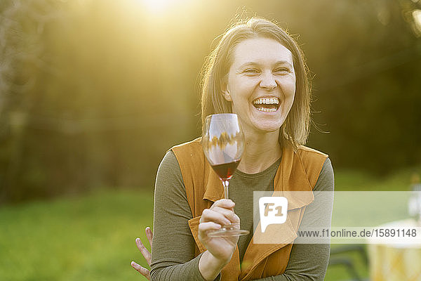 Happy woman drinking red wine in the countryside