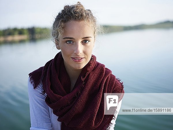Porträt einer jungen Frau am See  die in die Kamera schaut
