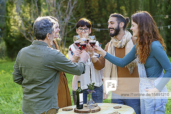 Group of friends toasting with red wine on their getaway in the countryside