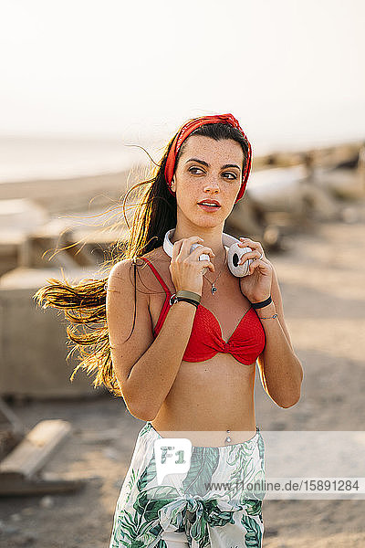 Junge Frau mit weißen Kopfhörern am Strand