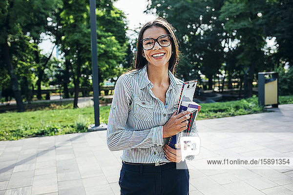 Lächelnde Studentin mit Büchern in einem Park