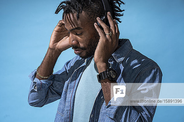 Portrait of stylish young man listening to music with headphones