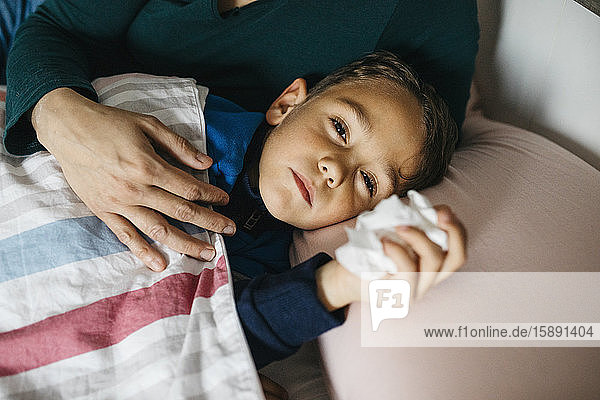 Porträt eines kranken kleinen Jungen im Bett liegend