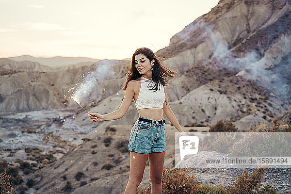 Portrait of smiling young woman with sparkler at sunset  Almeria  Spain