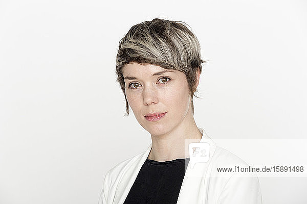 Portrait of woman with dyed short hair against white background