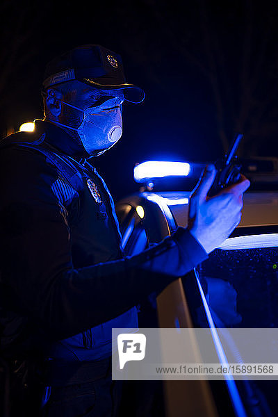 Policeman on emergency mission wearing face mask holding phone