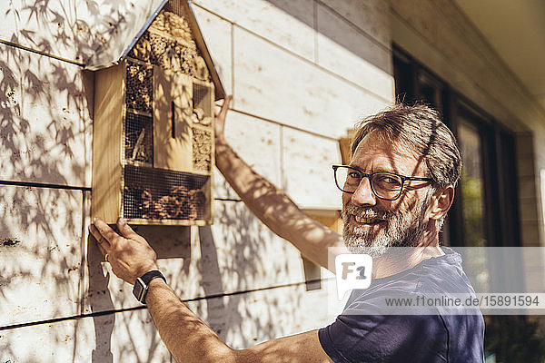 Porträt eines Mannes  der ein Insektenhotel befestigt