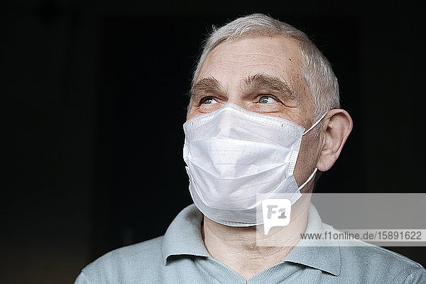 Porträt eines älteren Mannes  der zu Hause eine Maske trägt