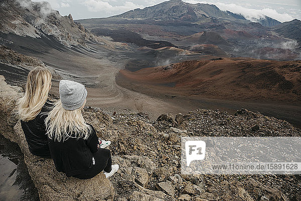 Rückansicht von Freundinnen  die am Haleakala-Krater sitzen  Maui  Hawaii  USA