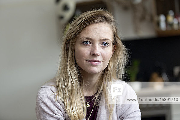 Porträt einer blonden jungen Frau mit blauen Augen zu Hause