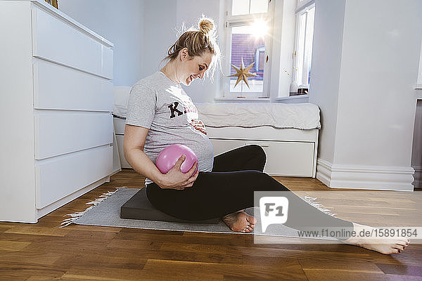 Schwangere Frau übt zu Hause mit einem Ball