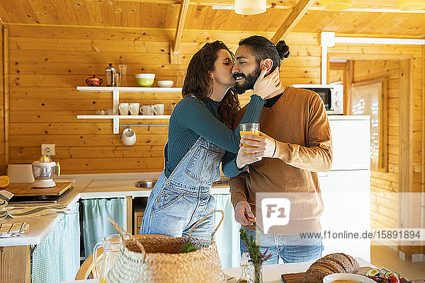 Junges Paar umarmt und küsst sich in einer Holzhütte