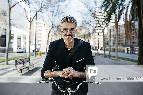 Porträt eines grauhaarigen Geschäftsmannes mit Fahrrad in der Stadt