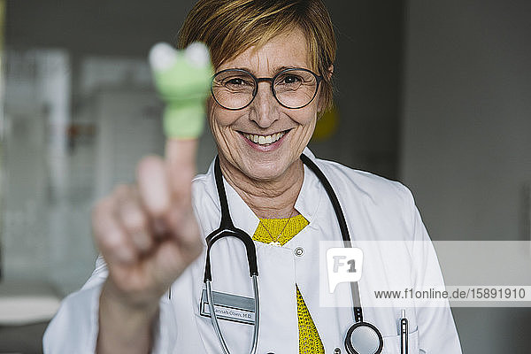 Portrait of happy doctor with finger doll