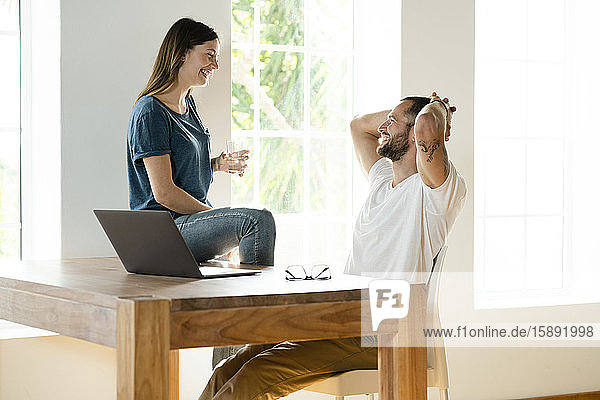 Glückliches Paar mit Laptop im Heimbüro im modernen Wohnzimmer