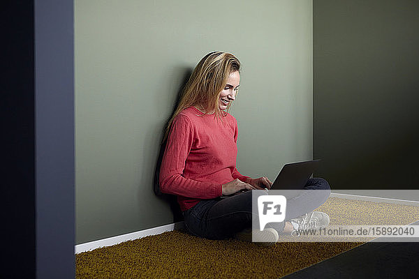 Smiling womansitting on the floor using laptop