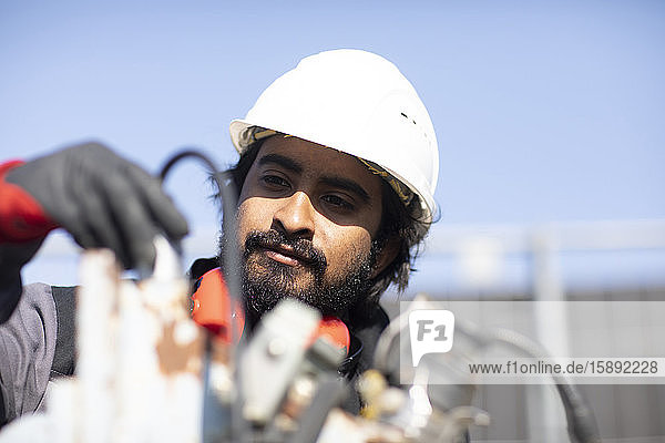 Porträt eines Technikers mit Helm und Bart bei der Arbeit