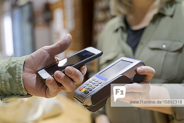 Customer paying contactless with smartphone in a shop