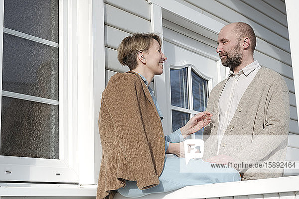 Glückliches Paar im Gespräch auf der Veranda ihres Hauses