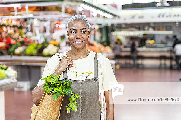 Porträt einer lächelnden Frau  die in einer Markthalle Lebensmittel einkauft