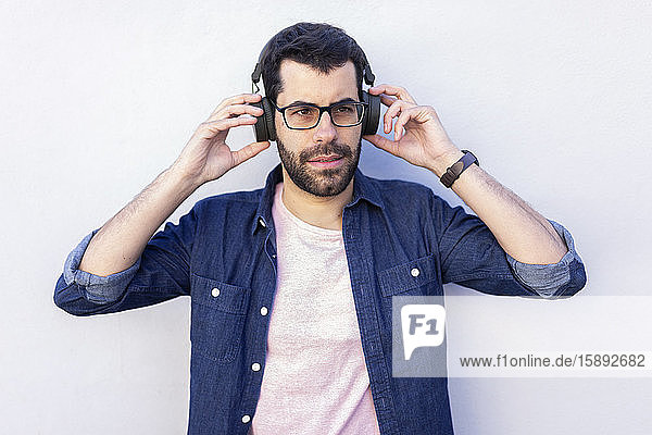 Porträt eines bärtigen Mannes  der mit drahtlosen Kopfhörern Musik hört