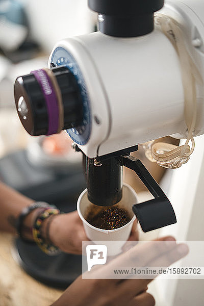 Nahaufnahme einer Frau  die Kaffee aus einer Maschine in eine Tasse gießt