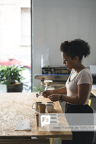 Frau  die in einer Kaffeerösterei arbeitet und Kaffee zubereitet