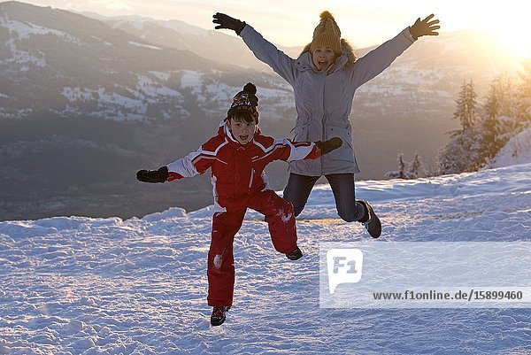 Boy and mother jumping on snow.