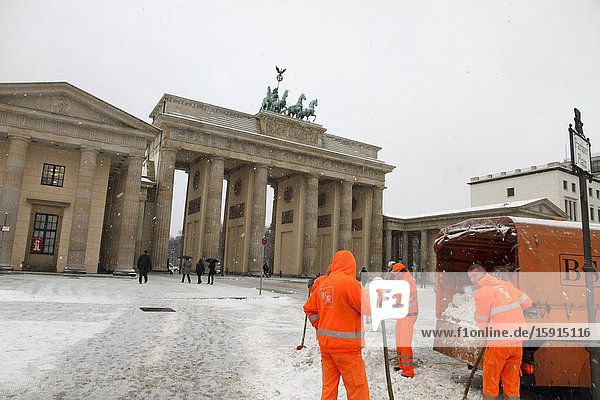 Berlin Brandenburg gate snowing with street cleaners Germany.