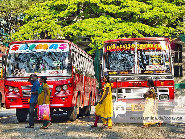People walking in front of two red buses Fort Cochin Fort Kochi Kerala India.