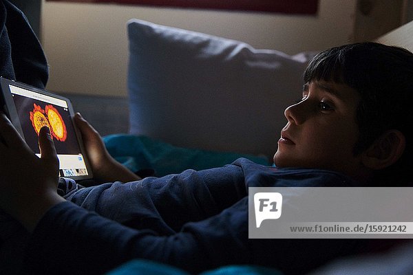 A little boy watches a image of coronatavirus in his iPad on the bed in his room due to the corona crisis. The Spanish government ordered all schools and public places to be closed until further notice in attempt to control the spread of the COVID-19 Coronavirus.