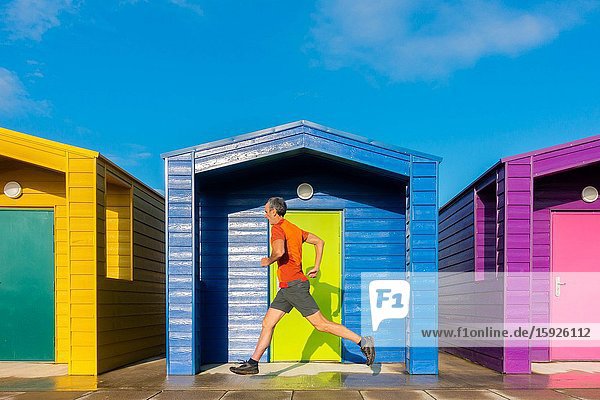 Mature jogger running past beach huts at Seaton Carew on the north east coast of England. Unite Kingdom.