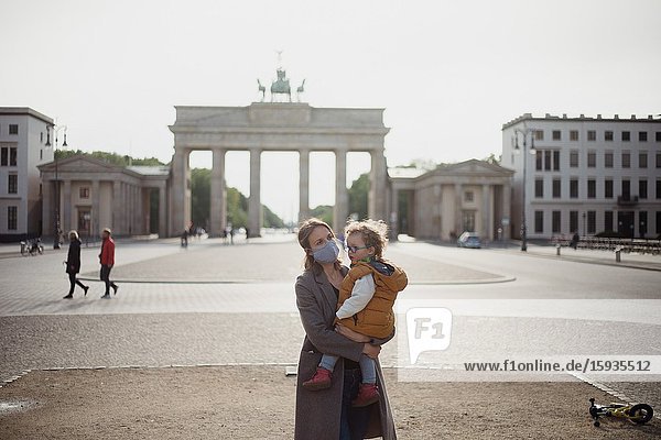 Mother and son walking with mask in Berlin in an empty Brandenburg gate during Corona time.