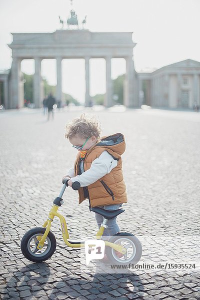 Little boy 2-3 Years old with bicycle and mask in front of Brandenburg gate in Berlin.