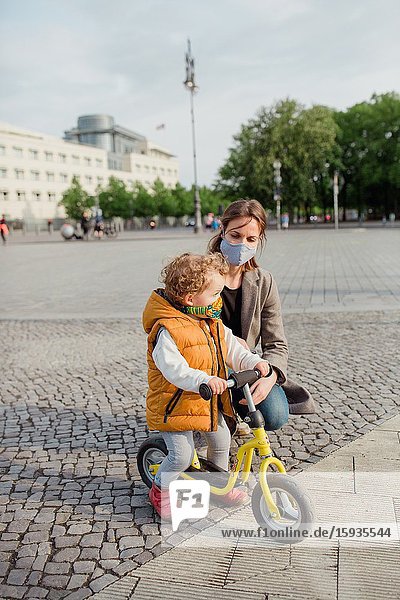 Little boy 2-3 years old with mask and bicycle in Berlin.