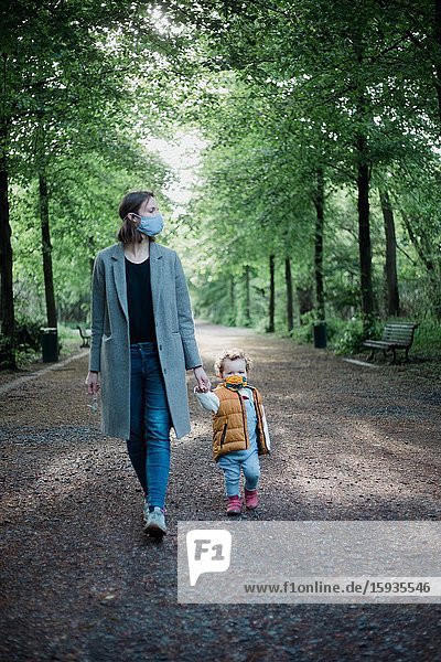 Mother and son walking in the park with mask during corona time.