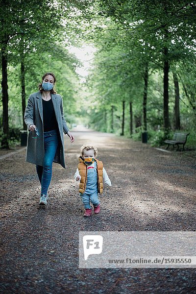 Mother and son walking in the park with mask during corona time.