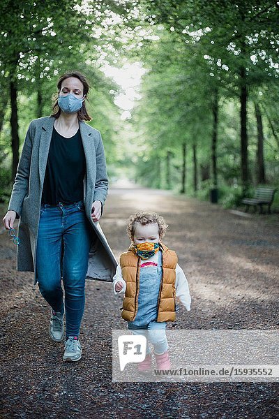 Mother and son walking in the park with mask during corona time.