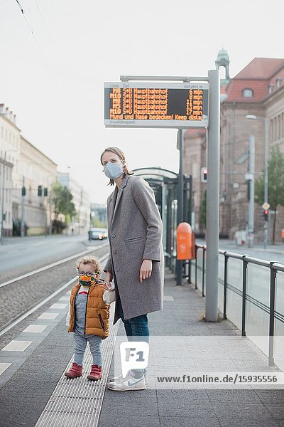 Mother and son with mask waiting for the bus.