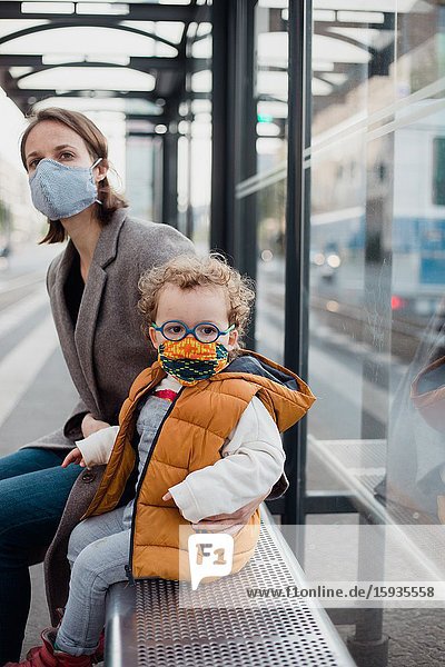 Mother and son with mask waiting for the bus.