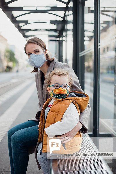 Mother and son with mask waiting for the bus.
