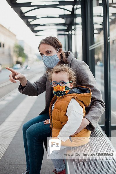 Mother and son with mask waiting for the bus.